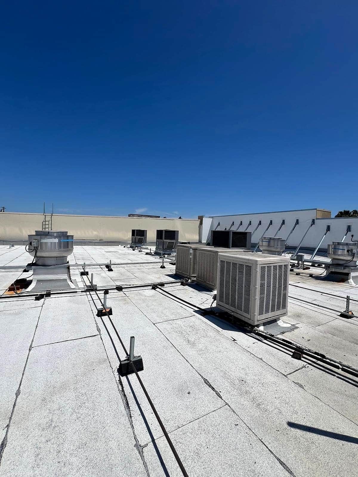 Packaged HVAC units on a commercial flat roof under a clear sky
