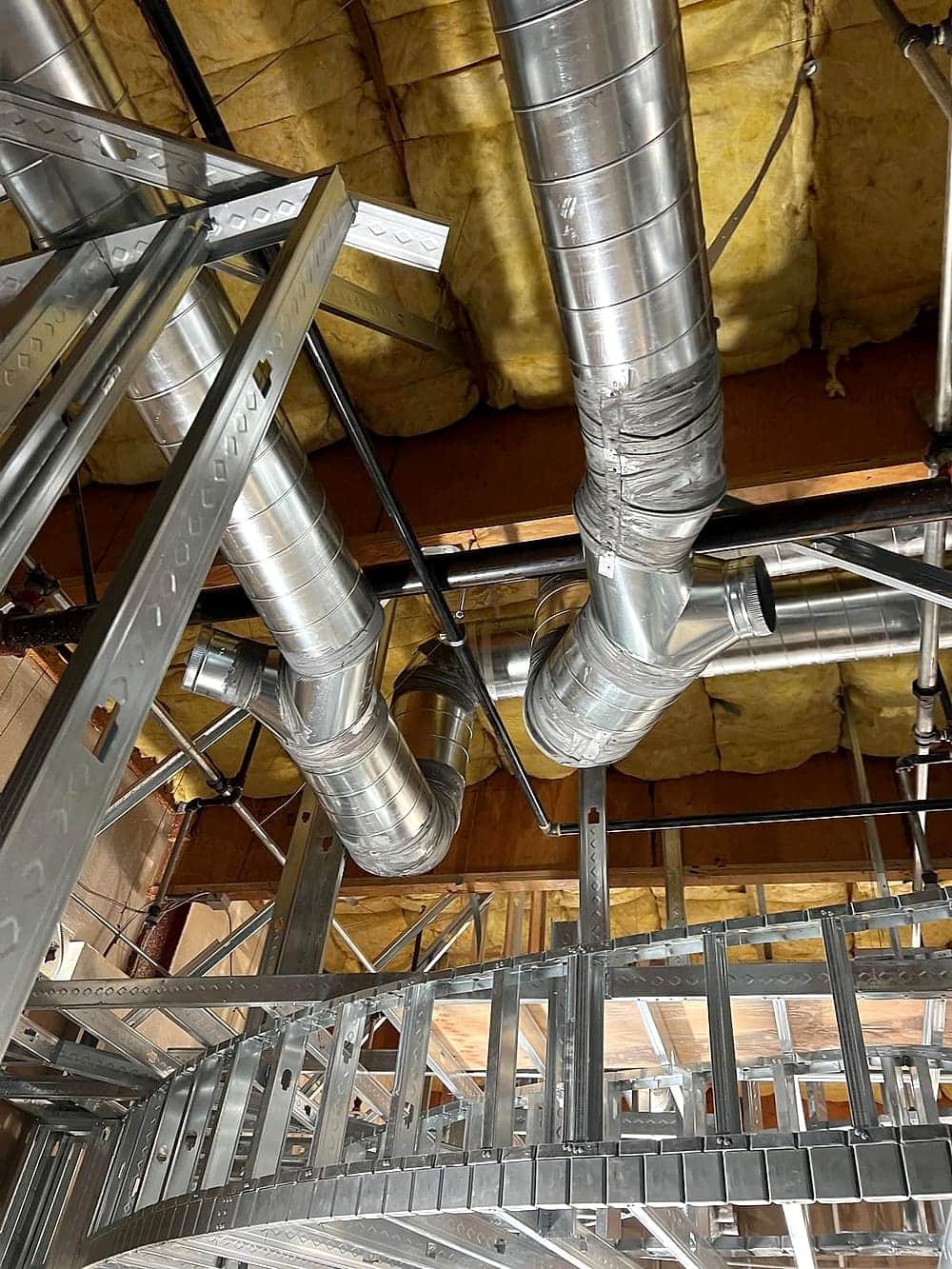 Round duct distribution routed through steel stud framing with insulation
