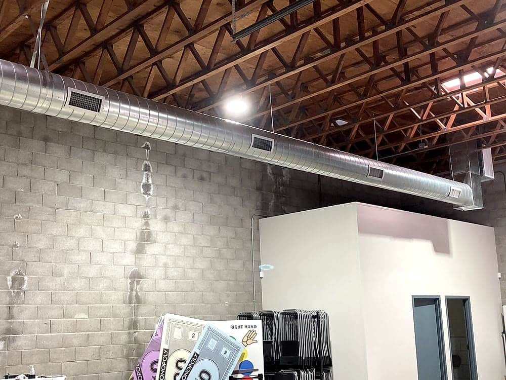Exposed spiral duct run under wood trusses in a warehouse