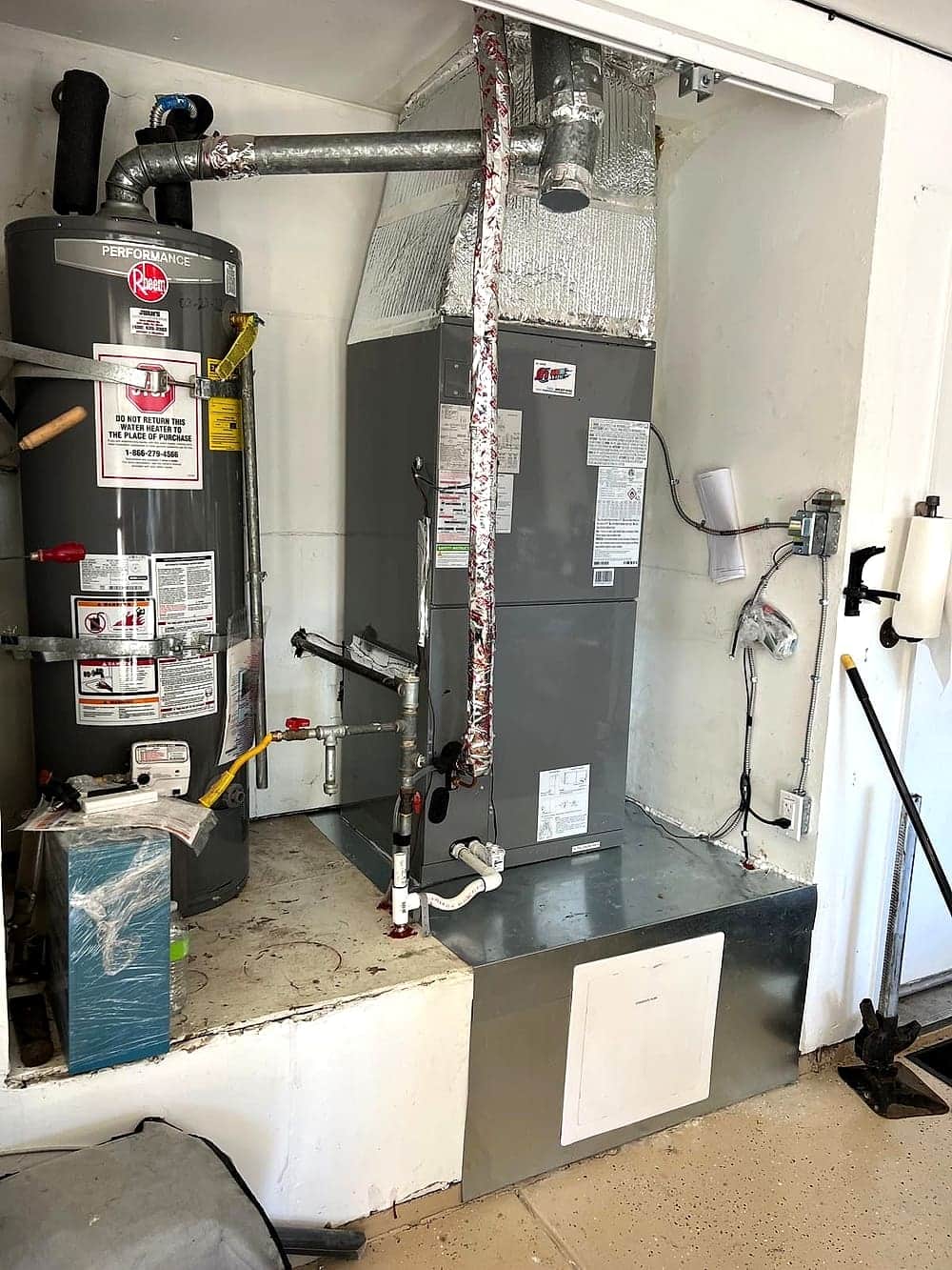 Gas water heater installed beside a furnace in a garage