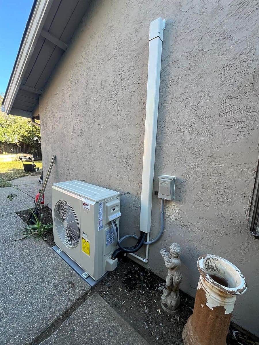 Ductless mini-split condenser with line-hide cover on a stucco wall